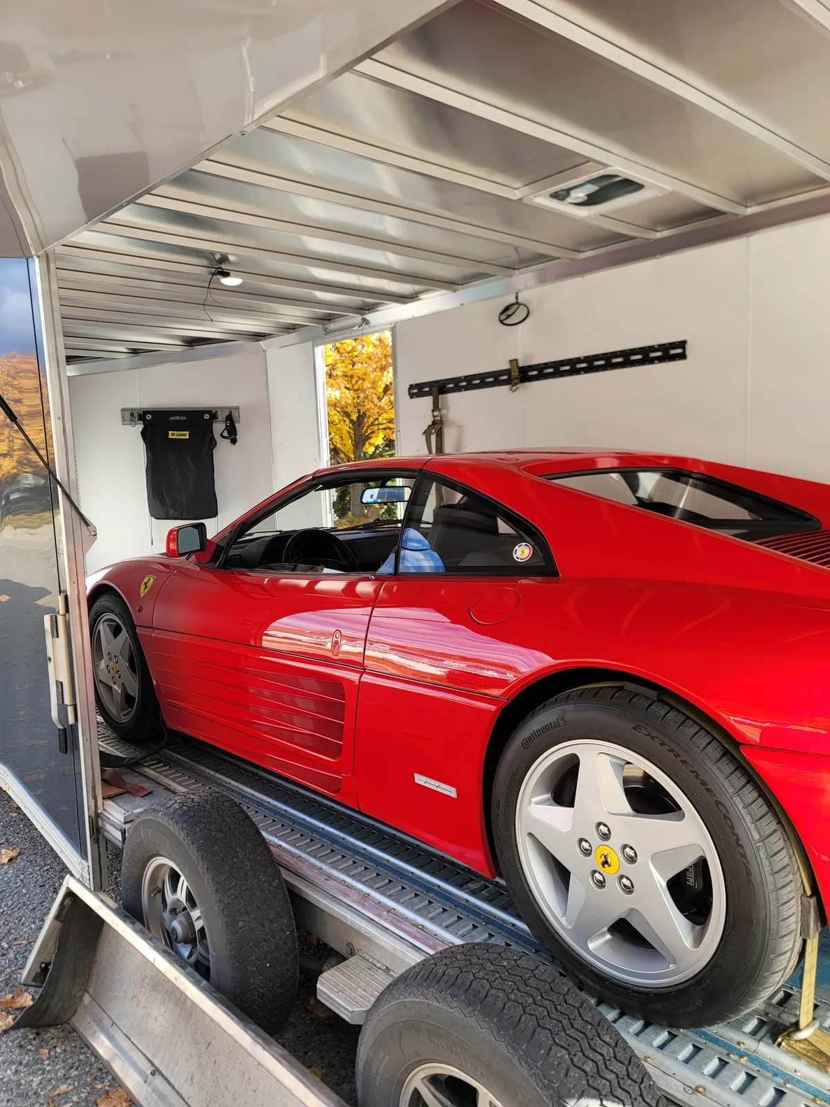 Red Ferrari 348 secured inside an enclosed transport trailer.